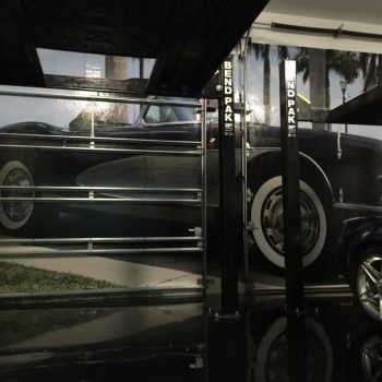 Garage interior featuring a large wall wrap of a classic car, with BendPak lift equipment visible, highlighting CRD Wraps' custom wall graphics.