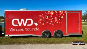 Custom vehicle wrap featuring a red trailer with "CWD. We care. You ride." text and vibrant graphic design, showcasing CRD Wraps' artistry and creativity in vehicle customization.