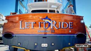Custom wood transom with "Let It Ride" text and logo, showcasing CRD Wraps craftsmanship for marine vehicle design.