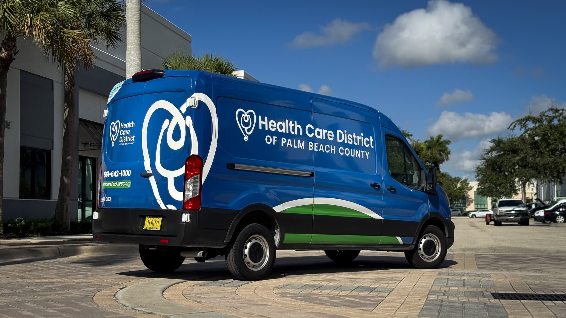 Rear and driver-side fleet branding on a Health Care District of Palm Beach County Ford Transit