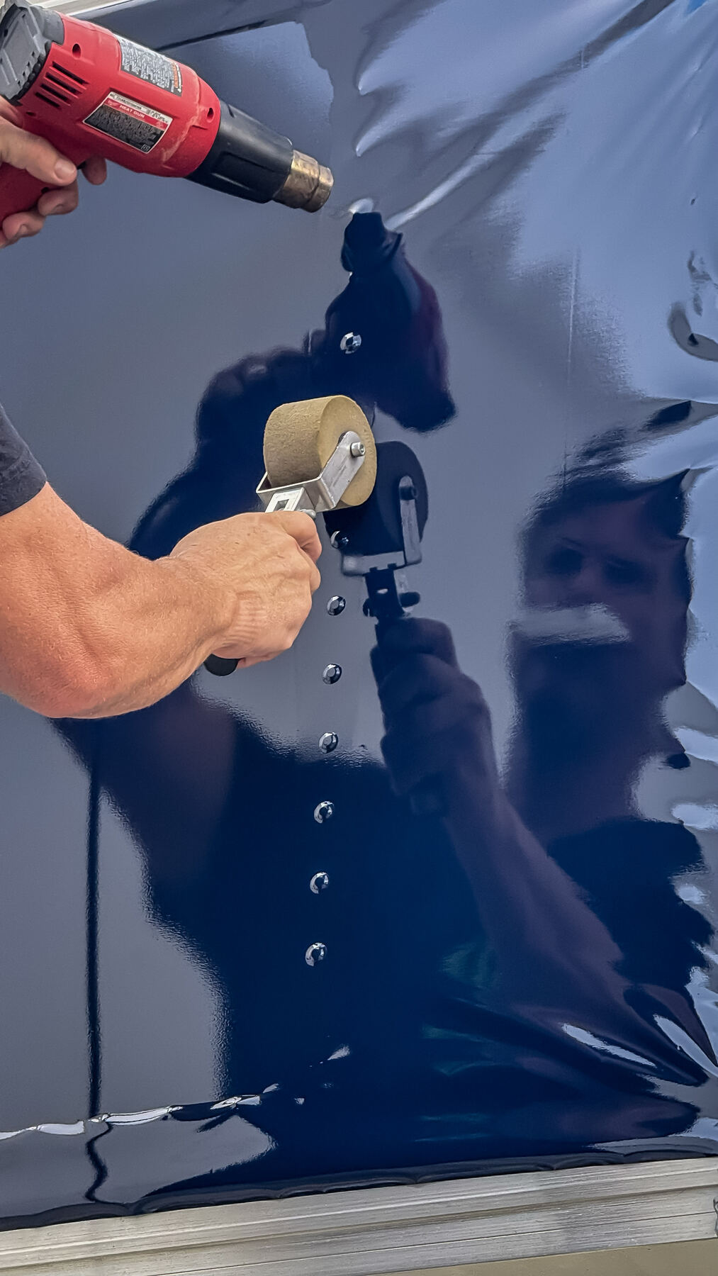 Close-up of cast vehicle wrap film being formed around box truck rivets using heat and an installation roller